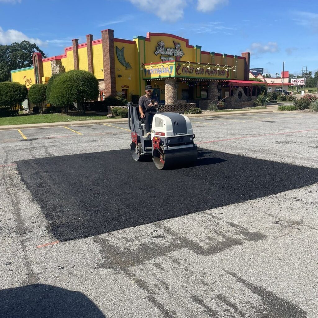 Asphalt patch repair being rolled in a restaurant parking lot in Denison, TX